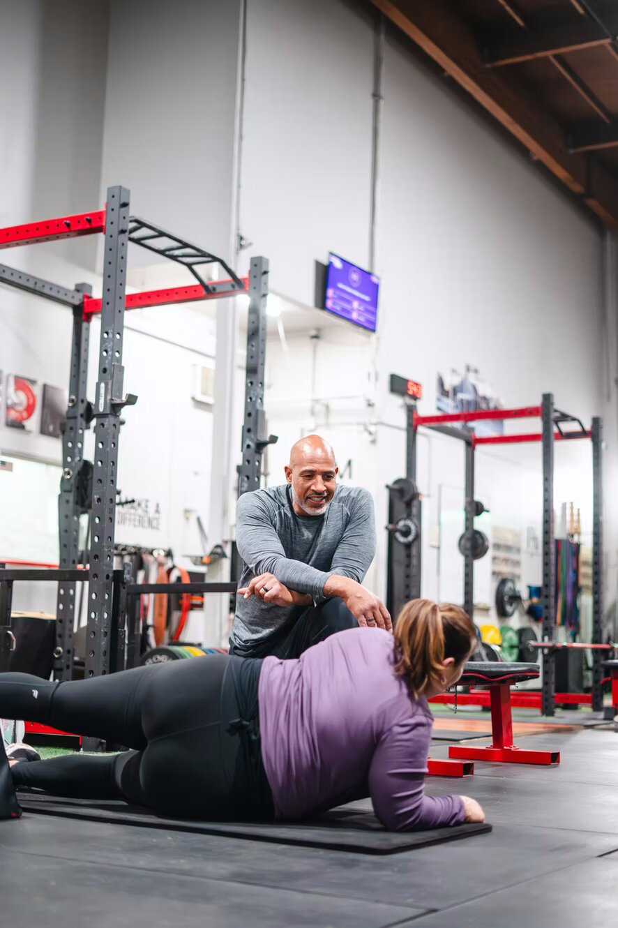A MaxFit coach guiding a client through floor work