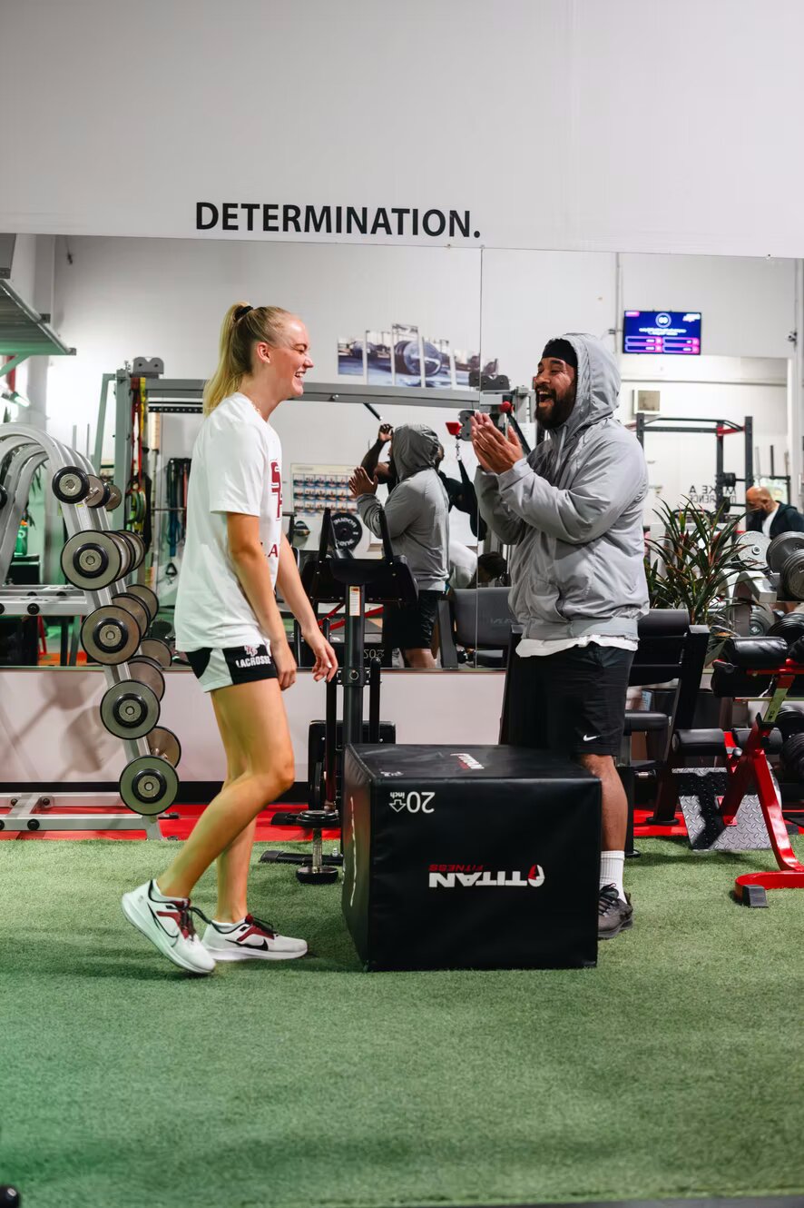 Coach with a client on the gym floor in front of the Determination wall